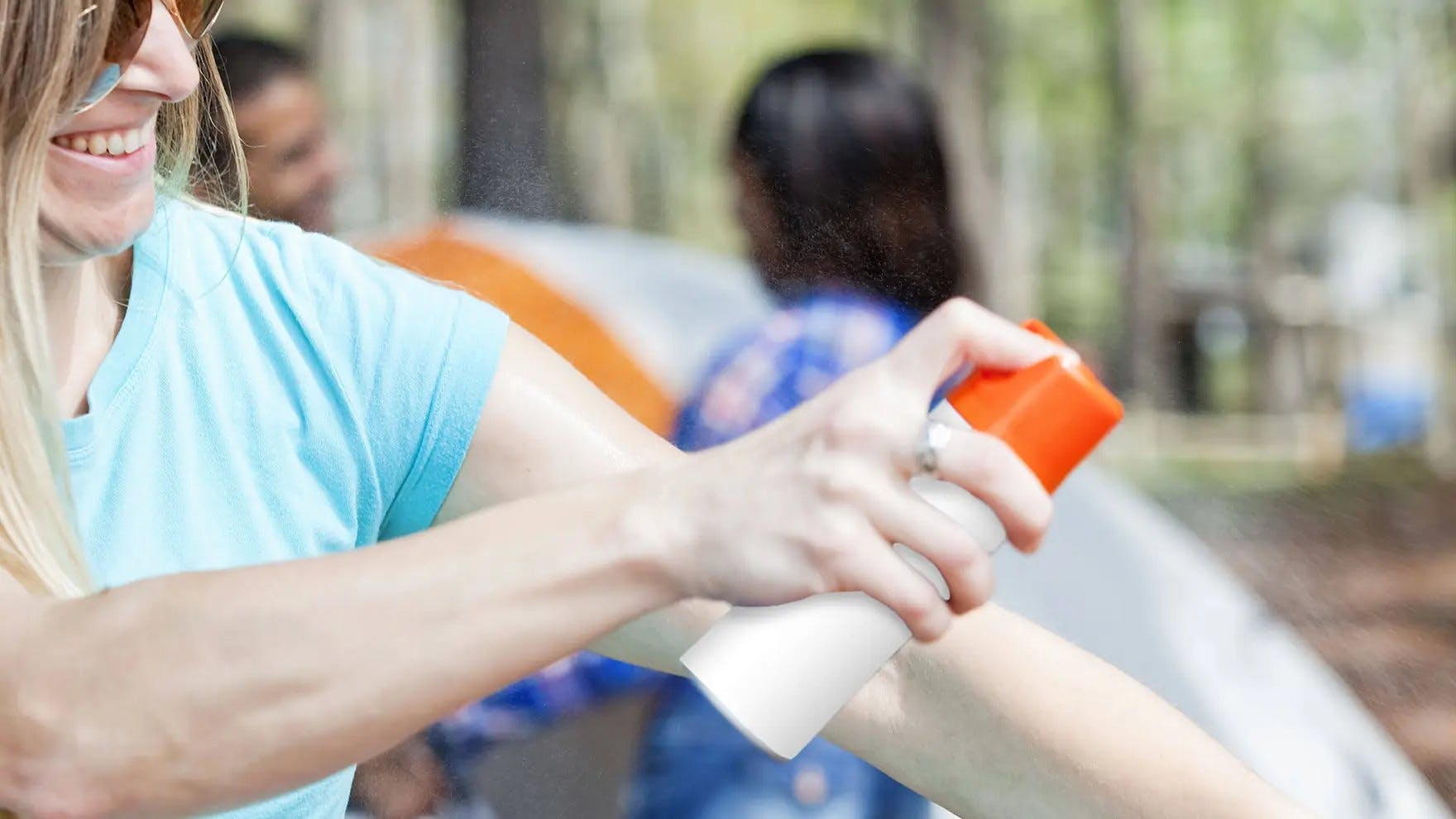 Woman spraying insect repellent on her arm