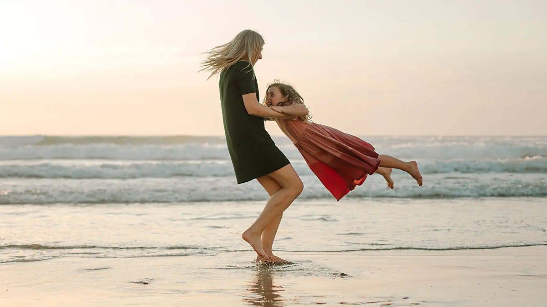 Un padre balanceando a un niño en brazos en la playa